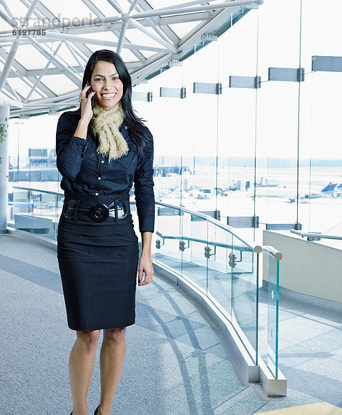 Geschäftsfrau telefoniert mit Handy am Flughafen