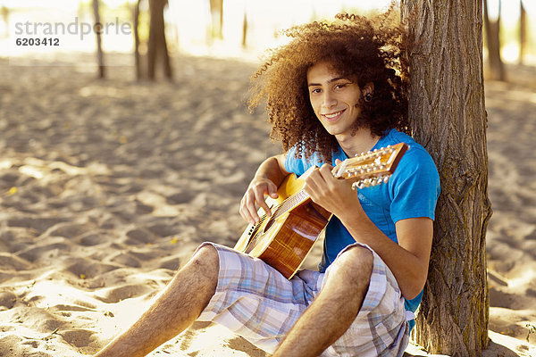 sitzend  Jugendlicher  Sand  mischen  Gitarre  musizieren  Musik machen  Mixed