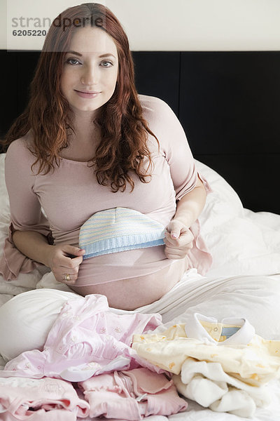 sitzend  Frau  Kleidung  Hispanier  Bett  Schwangerschaft  Baby