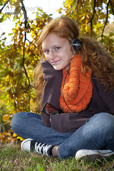 Mädchen mit roten Haaren hört Musik mit Kopfhörer und iPod