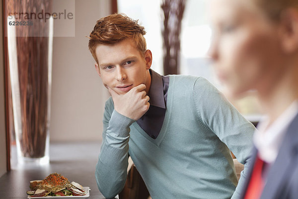 Mann in einem Restaurant mit Blick auf eine Geschäftsfrau