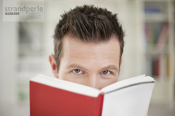 Porträt eines Mannes mit einem Buch vor dem Gesicht