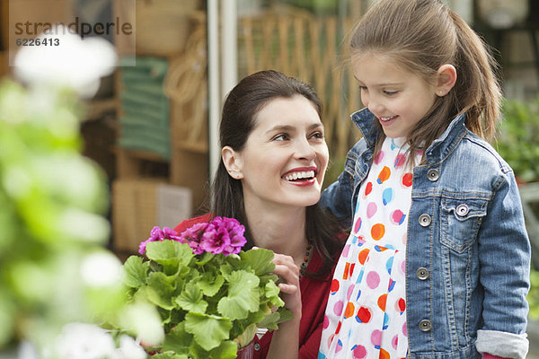 Frau und ihre Tochter schauen sich Blumen in einem Blumenladen an.