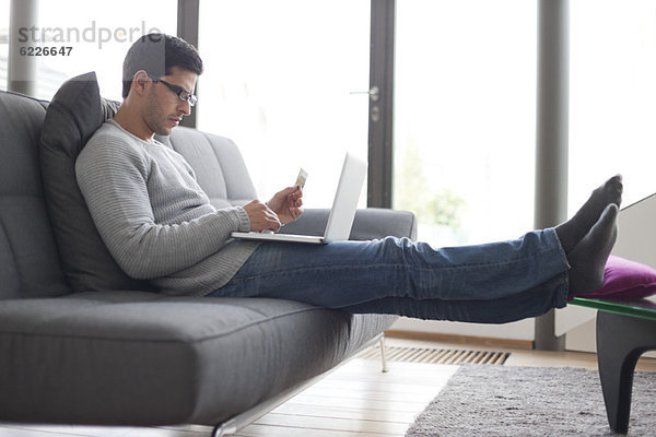 Mann mit Kreditkarte und Laptop