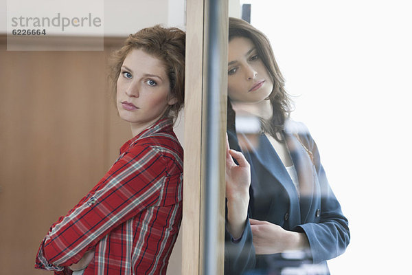 Zwei Freundinnen stehen Rücken an Rücken gegen eine Tür.
