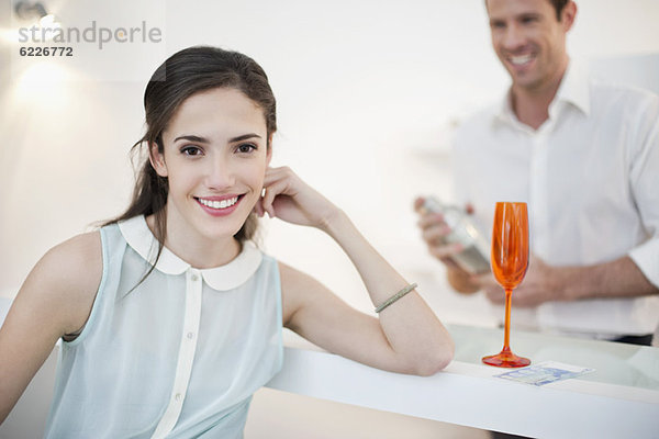 Frau lächelt mit ihrem Mann und schüttelt Cocktail im Hintergrund