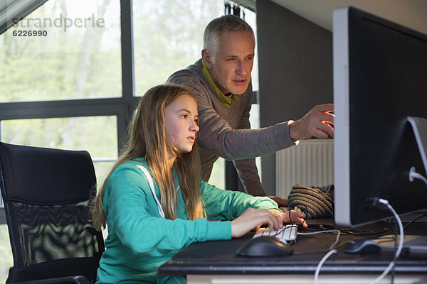 Mädchen am Computer mit ihrem Vater zu Hause