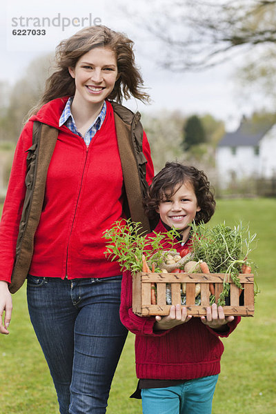 Mutter und Sohn mit einer Kiste mit einheimischem Gemüse