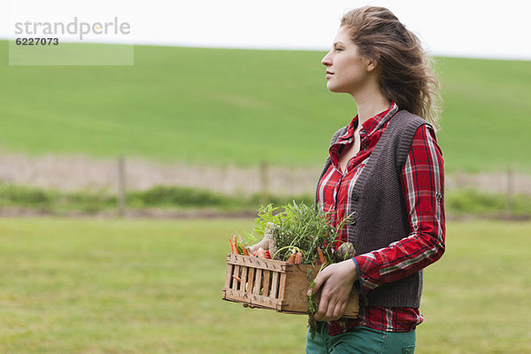 Frau hält einen Korb mit Gemüse auf einem Bauernhof