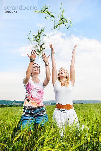 Zwei junge Frauen werfen Getreide in die Luft