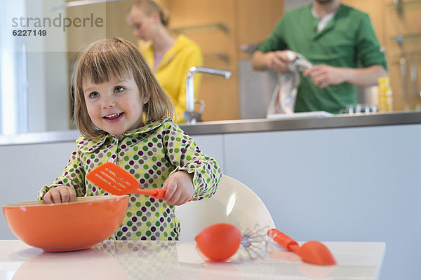 Süßes kleines Mädchen mit Schlitzlöffel und Rührschüssel in der Küche