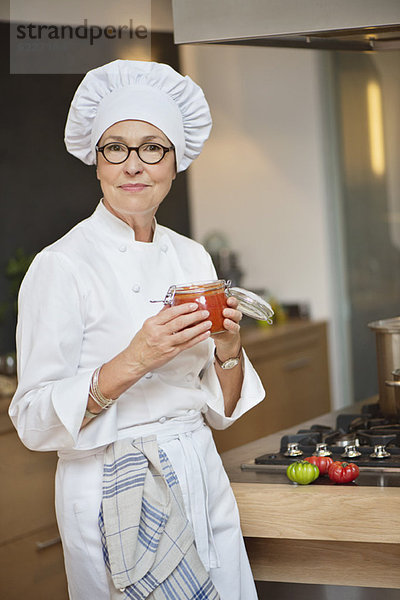Frau hält ein Glas Tomatensauce in der Hand