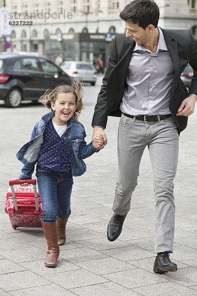 Mädchen beim Laufen mit ihrem Vater an einem Trolley ziehen