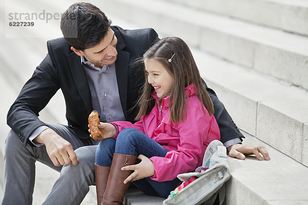 Mann sitzend mit seiner Tochter beim Essen von Schmerz au chocolat