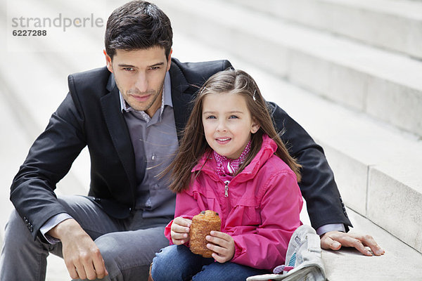 Mann sitzend mit seiner Tochter beim Essen von Schmerz au chocolat