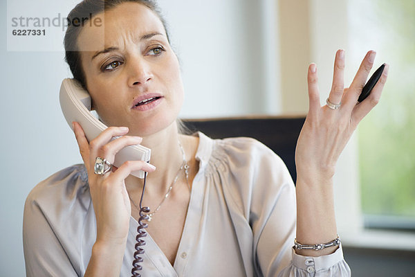Geschäftsfrau im Büro am Festnetztelefon