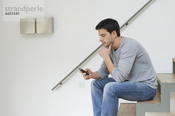 Mann  der mit dem Handy auf der Treppe sitzt