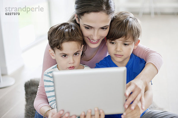 Frau zeigt ihren Kindern ein digitales Tablett
