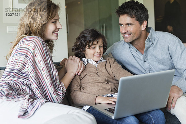 Junge mit Laptop bei seinen Eltern zu Hause