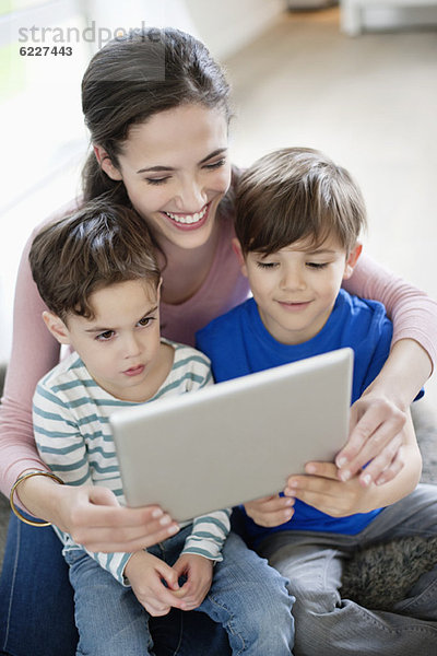 Frau zeigt ihren Kindern ein digitales Tablett