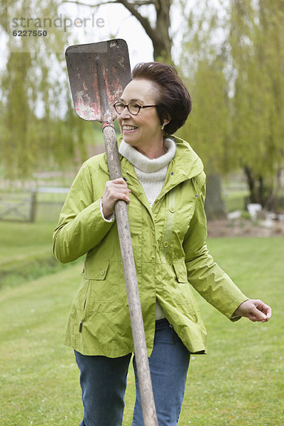 Frau geht mit dem Spaten im Park spazieren