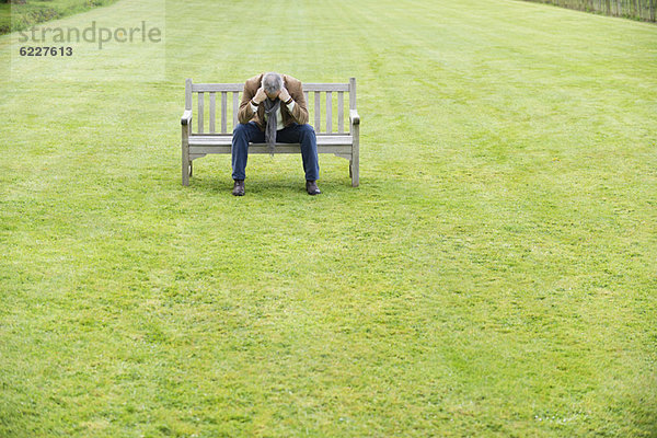 Depressiver Mann sitzt auf einer Bank in einem Park
