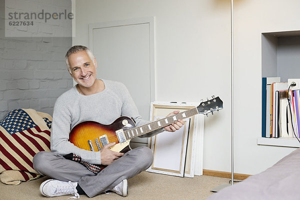 Porträt eines glücklichen Mannes beim Gitarrespielen