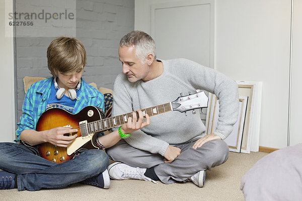 Teenager-Junge lernt Gitarre bei seinem Vater zu Hause