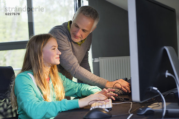 Mädchen am Computer mit ihrem Vater zu Hause