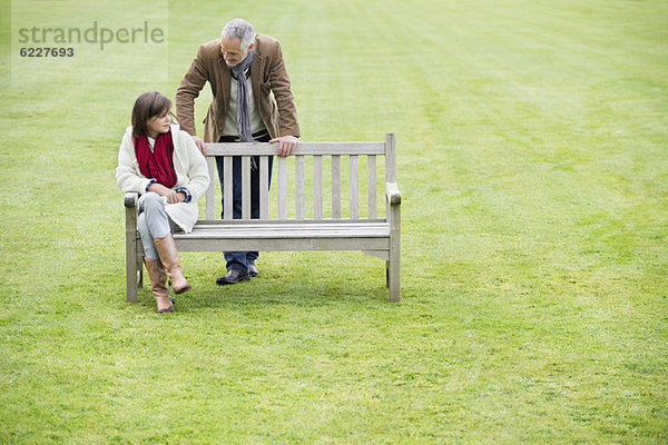 Mann sitzend mit seiner Tochter auf einer Bank im Park