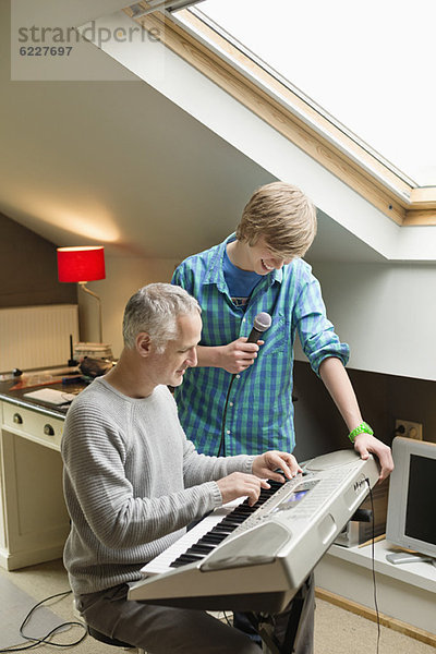 Ein Mann  der mit seinem Sohn zu Hause ein E-Piano spielt.