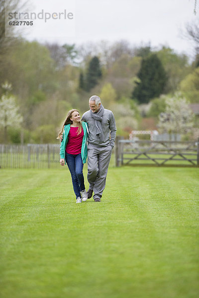 Ein Mann  der mit seiner Tochter auf einem Feld spazieren geht.