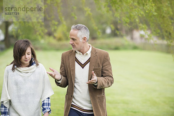 Mann diskutiert mit seiner Tochter beim Spaziergang im Park