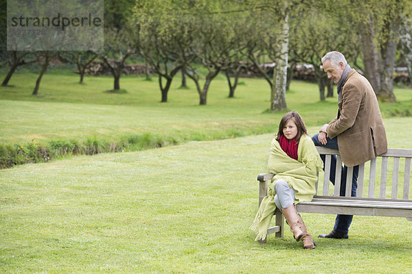 Mann sitzend mit seiner Tochter auf einer Bank im Park