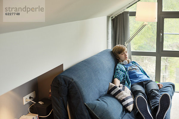 Teenager-Junge schläft zu Hause auf einer Couch