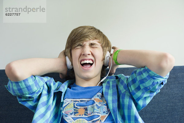 Teenager-Junge  der Musik hört und aufgeregt aussieht.