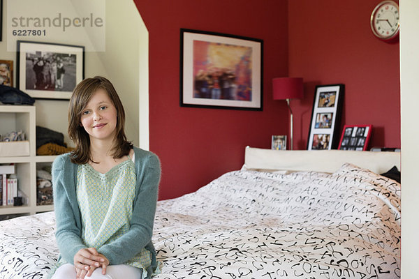 Porträt eines Mädchens auf dem Bett sitzend und lächelnd