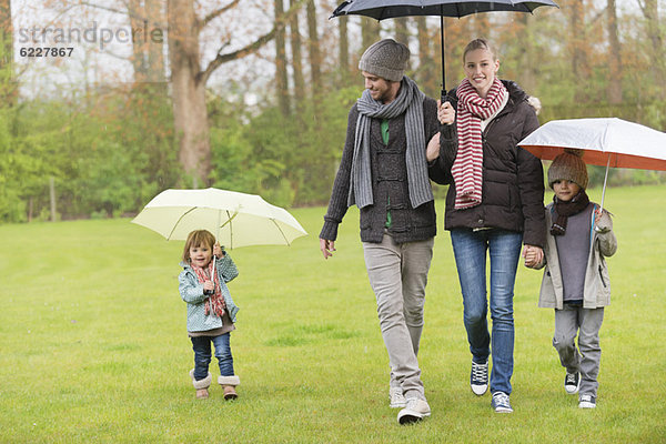 Familienwanderung mit Sonnenschirmen im Park