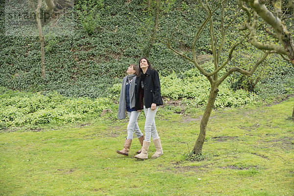 Frau mit ihrer Tochter  die in einem Obstgarten spazieren geht