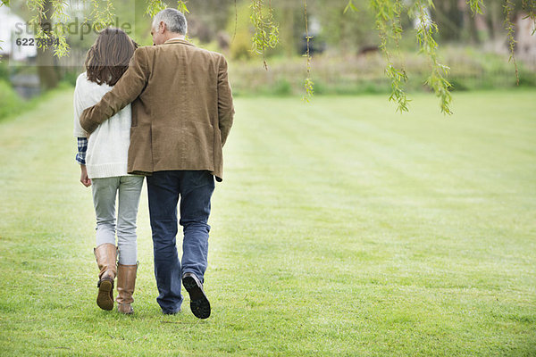 Ein Mann  der mit seiner Tochter im Park spazieren geht.