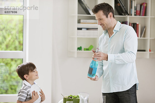 Mann zeigt seinem Sohn eine Sprudelwasserflasche
