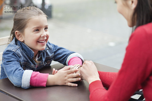 Mädchen sitzend mit ihrer Mutter in einem Straßencafé