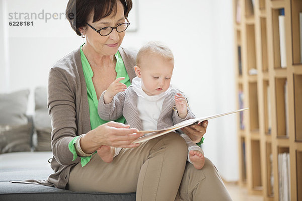 Frau mit ihrer Enkelin beim Lesen eines Bilderbuches