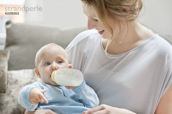 Babymädchen  das sich mit Milch füttert  mit einer Milchflasche