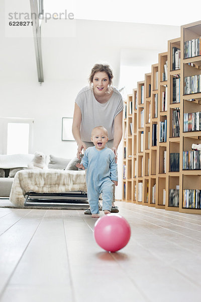 Frau spielt mit ihrer Tochter und geht auf einen Ball zu.