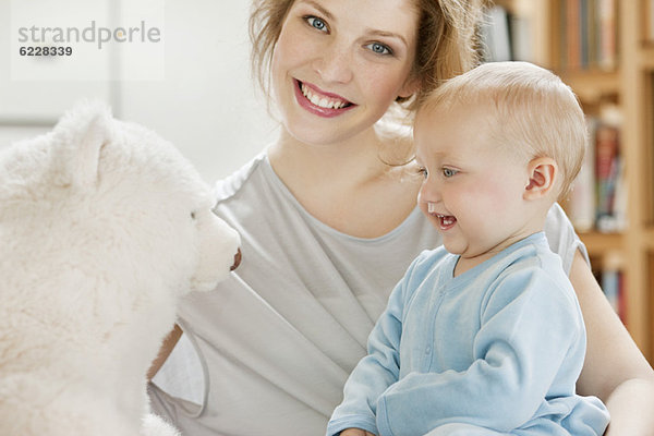 Baby Mädchen spielt mit einem Teddybär und lächelt