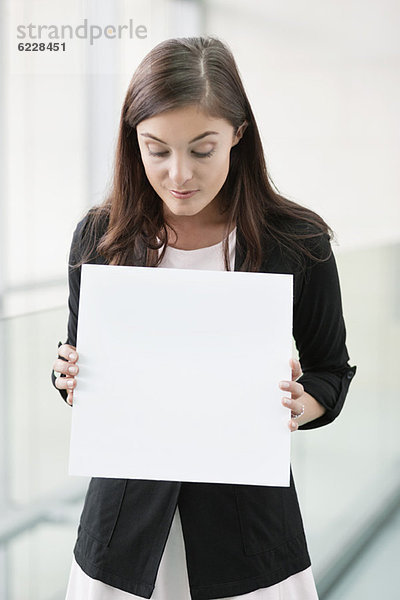 Geschäftsfrau mit einem leeren Plakat in einem Büro