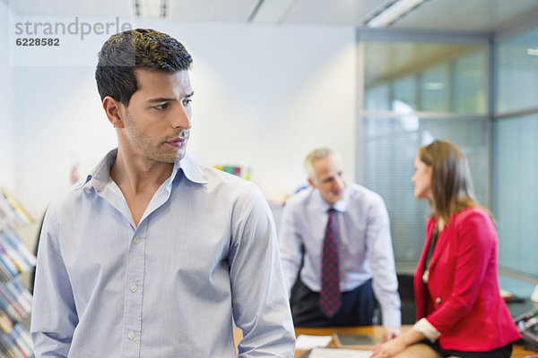 Männliche Führungskraft  die dem Gespräch seiner Kollegen in einem Büro zuhört
