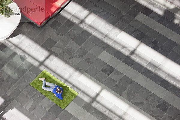 Geschäftsmann entspannt auf Rasen in einer Büro-Lobby