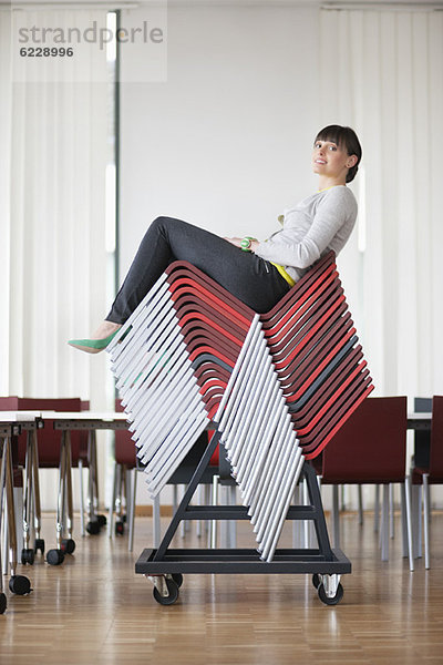 Geschäftsfrau sitzt auf Pile-Up-Stühlen in einem Büro